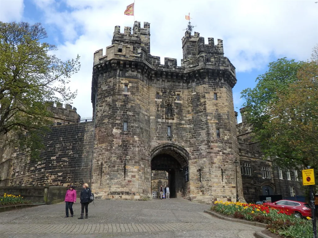 Lancaster Castle's medieval gatehouse from the cobbled approach, with spring flowers in bloom