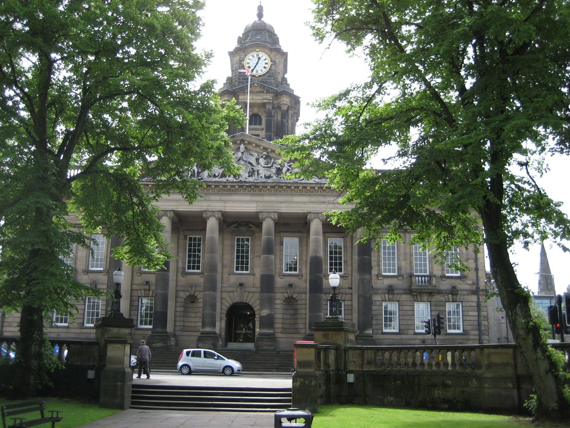 Lancaster Town Hall with its clock tower framed by trees on Dalton Square