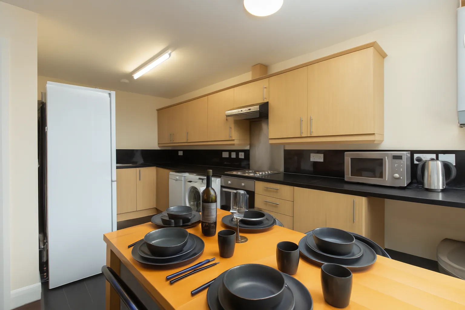 A fitted shared kitchen with the dining table set for dinner in a Bayt student home in Lancaster