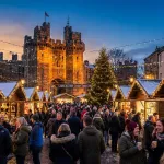 Lancaster Christmas Market in Market Square with illuminated stalls and Lancaster Castle at dusk for students